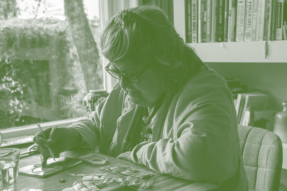 Oudere vrouw is thuis geconcentreerd bezig met een creatieve hobby