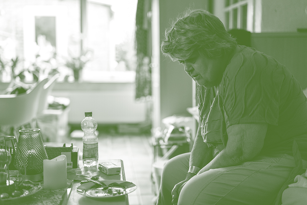 Oudere vrouw zit alleen aan de eettafel