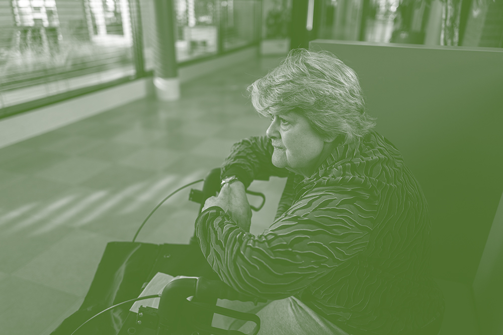 Oudere vrouw in rolstoel wacht in een ziekenhuisgang