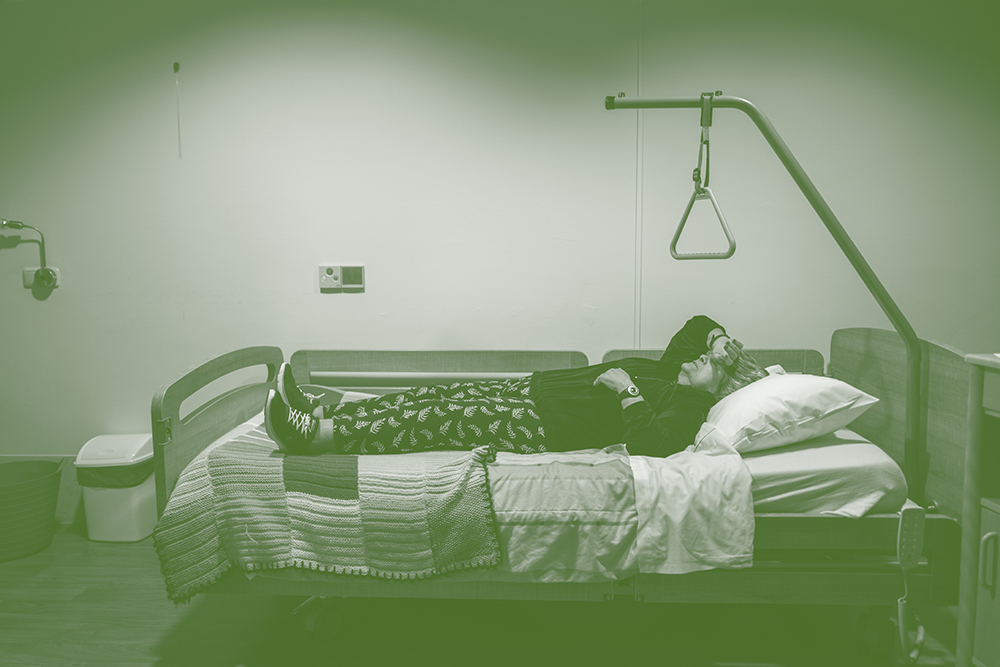 Persoon ligt uitgeput op een ziekenhuisbed